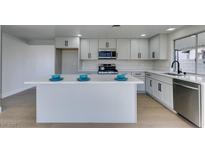 Modern kitchen features white cabinets, stainless steel appliances, island with quartz countertop and stylish finishes at 2205 Mccoig Ave, Las Vegas, NV 89119