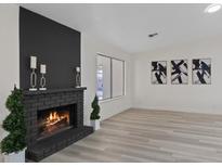 Bright living room boasts a brick fireplace, black accent wall, and decorative artwork at 7138 Sixshooter Dr, Las Vegas, NV 89119