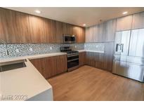 Modern kitchen featuring stainless steel appliances, light countertops, mosaic backsplash, and wood-look flooring at 150 N Las Vegas Blvd # 2302, Las Vegas, NV 89101
