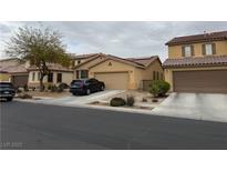 Charming single-Gathering home featuring a two-car garage, desert landscaping, and solar panels on the roof at 8260 Mesa Bloom St, North Las Vegas, NV 89085