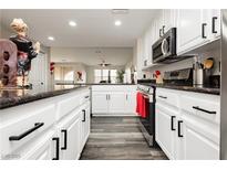 Modern kitchen featuring white cabinets, black hardware, stainless steel appliances, and dark countertops at 10091 Sand Key St, Las Vegas, NV 89178