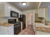 Bright kitchen features white cabinets, black appliances, tile counters and flooring, and adjacent pantry at 2120 Ramrod Ave # 415, Henderson, NV 89014