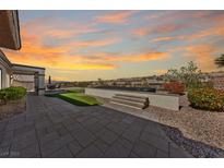 Beautiful backyard featuring a putting green, patio, and hot tub with desert views during a colorful sunset at 2920 Foxtail Creek Ave, Henderson, NV 89052