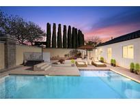 Beautiful backyard pool with lounge chairs and manicured landscaping at dusk at 3197 Castle Canyon Ave, Henderson, NV 89052