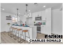 Bright, modern kitchen features a large island with seating, white cabinets and stainless steel appliances at 4500 Charles Ronald Ave, Las Vegas, NV 89121