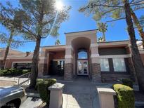 Condo building exterior featuring stone accents, architectural arch, and mature trees at 1505 Blackcombe St # 103, Las Vegas, NV 89128