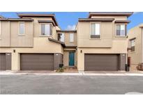 Modern townhome featuring a two-car garage, desert landscaping and a vibrant teal-colored front door at 752 Echelon St, Las Vegas, NV 89138