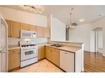 Bright kitchen features wood cabinets, white appliances, and tiled flooring at 8787 Roping Rodeo Ave # 101, Las Vegas, NV 89178