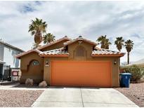 Charming single-story home with desert landscaping, palm trees, and an orange two-car garage door at 5430 Lonesome Biker Ln, Las Vegas, NV 89113