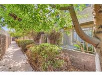 Charming exterior view with mature trees, garden, and fenced patio for privacy and outdoor living at 6412 Big Pine Way, Las Vegas, NV 89108