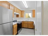 Bright kitchen features wood cabinets, stainless steel appliances, and sleek countertops at 6867 Tamarus St # 204, Las Vegas, NV 89119