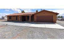 Single story home with a desert landscape, neutral colored paint, tile roof and an attached garage at 1081 Pluto St, Pahrump, NV 89048