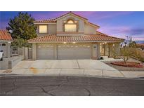 Two-story home with a tile roof and a three-car garage provides an inviting curb appeal at 2021 Summit Pointe Dr, Las Vegas, NV 89117