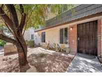 Charming condo exterior with a secure iron door and desert landscaping and mature shade tree at 3944 Visby Ln, Las Vegas, NV 89119
