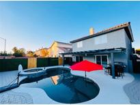 Backyard pool with red umbrella, hot tub, and barbecue area provide a great outdoor living and entertaining space at 5705 Enchanted Palms Ave, Las Vegas, NV 89139