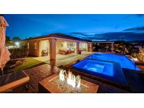 Inviting backyard features a luxurious pool, spa, covered patio, and cozy fire pit, perfect for outdoor relaxation at 8298 W Agate Ave, Las Vegas, NV 89113