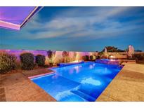 Beautiful pool with a waterfall feature and an outdoor kitchen area, perfect for entertaining on warm evenings at 8298 W Agate Ave, Las Vegas, NV 89113
