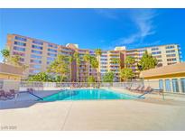 Inviting outdoor pool and lounge area with mature landscaping and beautiful surrounding building at 205 E Harmon Ave # 707, Las Vegas, NV 89169