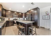 A large kitchen with an island and dark wood cabinets has stainless steel appliances at 3920 Clear View Dr, Las Vegas, NV 89121