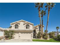 Two-story home with a three-car garage, mature palm trees, and well-manicured lawn, offering curb appeal at 1044 Trophy Club Dr, Las Vegas, NV 89123