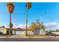 Charming single-story home with a white garage door and well-kept front yard with mature trees at 2500 Holly Ave, Las Vegas, NV 89106