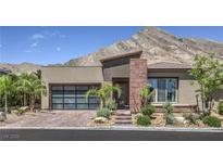 Modern home featuring beautiful desert landscaping, a glass garage door and striking mountain views at 11185 Black Fire Opal Dr, Las Vegas, NV 89138