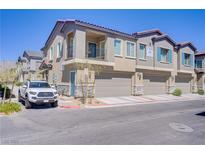 Two-story townhome featuring a private garage and covered entrance with blue accents against a beige stucco facade at 7350 N Decatur Blvd # 5, Las Vegas, NV 89131