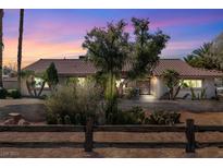 Wide front exterior view of this single-story home featuring desert landscaping, a brick driveway and mature trees at dusk at 800 Kenny Way, Las Vegas, NV 89107