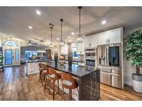 Modern kitchen featuring a spacious island with a waterfall edge, stainless steel appliances, and wood flooring at 417 Madison Taylor Pl, Las Vegas, NV 89144