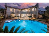 Expansive swimming pool at the rear of an elegant two-story home with manicured landscaping and sunset views at 501 Proud Eagle Ln, Las Vegas, NV 89144
