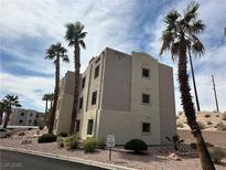Three-story condo building featuring desert landscaping and multiple palm trees at 2072 Mesquite Ln # 102, Laughlin, NV 89029