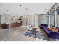 Modern condo lobby with front desk and lounge area with purple sofa and floor to ceiling windows at 353 E Bonneville Ave # 375, Las Vegas, NV 89101