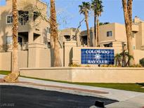 A tan stucco complex entry featuring mature palm trees and an identifying 
