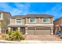 Two-story home with a beige facade, a two-car garage, and a brick driveway at 6484 Mount Eden Ave, Las Vegas, NV 89139