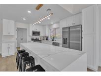 Modern kitchen features white cabinets, stainless steel appliances, and a large island with stylish seating at 8812 Stoney Point Dr, Las Vegas, NV 89134
