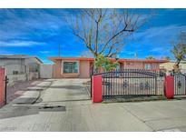 Single story home with a driveway behind a fence and a beautiful blue sky at 1113 Date St, Las Vegas, NV 89108