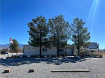 Charming single story home with desert landscaping, mature trees, and long driveway on a sunny day at 4861 Pahrump Valley Blvd, Pahrump, NV 89048