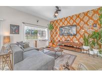 Inviting living room featuring a large sectional, distinctive wallpaper, and abundant natural light at 4921 Cedar Lawn Way, Las Vegas, NV 89130