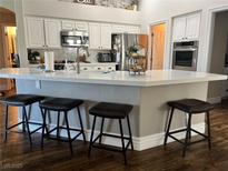 Bright kitchen features white cabinetry, stainless steel appliances, and a large island with seating at 8319 Browns Mountain Ct, Las Vegas, NV 89131