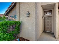 Home's front door with classic sconces and a tidy green hedge, offering curb appeal and a warm welcome at 3667 Edinburgh Dr, Las Vegas, NV 89103