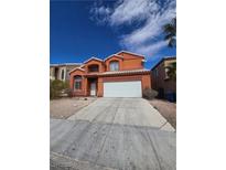 Charming two-story home with orange stucco exterior and a two car garage on a sunny day at 8124 Kokoma Dr, Las Vegas, NV 89128