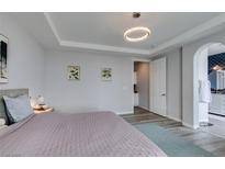Bedroom with a tray ceiling, an elegant light fixture, and an ensuite bathroom featuring an arched doorway at 11769 Via Vera Cruz Ct, Las Vegas, NV 89138