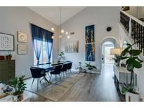 Bright dining room featuring hardwood floors, high ceilings, and stylish modern lighting fixture at 11769 Via Vera Cruz Ct, Las Vegas, NV 89138