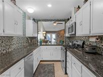 Bright kitchen features white cabinetry, mosaic backsplash, and granite counters with stainless steel appliances at 321 Yardarm Way, Las Vegas, NV 89145