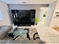 Living room featuring a large television with black stand and grey tile flooring at 6750 Del Rey Ave # 133, Las Vegas, NV 89146