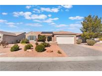 Charming single-story home showcasing desert landscaping, a two-car garage, and solar panels on the roof at 2115 Colvin Run Dr, Henderson, NV 89052