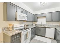 Updated kitchen features gray cabinets, granite counters, and modern white appliances at 3151 Soaring Gulls Dr # 1110, Las Vegas, NV 89128