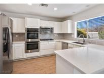 Bright kitchen with white cabinets, stainless steel appliances, and a large island with quartz countertops at 9028 Firebird Dr, Las Vegas, NV 89134