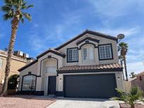 Charming two-story home featuring a tile roof, a two-car garage, and mature palm trees in the front yard at 9139 Scallop Reef Ave, Las Vegas, NV 89147