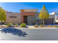 Modern home featuring a stylish facade with mixed materials, desert landscaping, and a two-car garage at 10879 Artesano Ave, Las Vegas, NV 89135